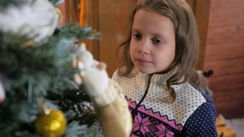 Young girl in hat putting ornament on Christmas tree Stock Footage 82452053