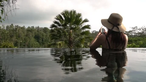 Young girl in the hat using a phone in the pool in Bali, Indonesia. Stock Footage 104222058