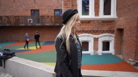 A young girl in a hat walks down the street and poses for the camera. Stock Footage 266440448