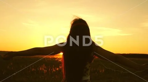 Young girl in headphones and with a smartphone whirl in flight under the rays of Stock Photos