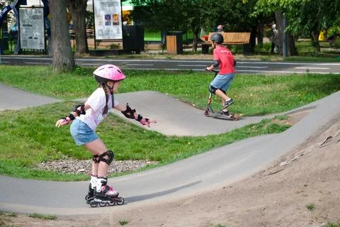 Young Girl Inline Skating While Boy Rides Kick Scooter Stock Photos