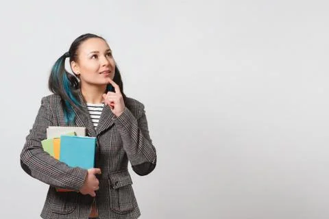 A young girl in a jacket with a stack of books in her hands. gaze directed at Stock Photos
