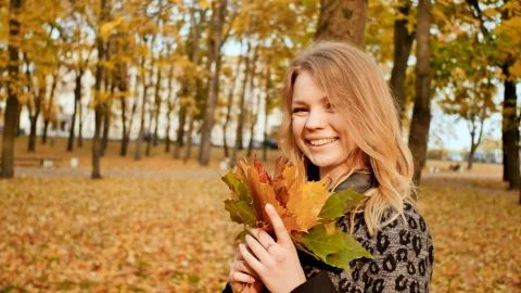 A young girl joyfully posing on the camera with a bouquet of colorful leaves Stock Illustration