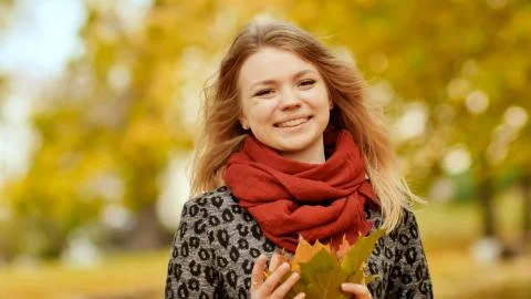 A young girl joyfully posing on the camera with a bouquet of colorful leaves Stock Illustration
