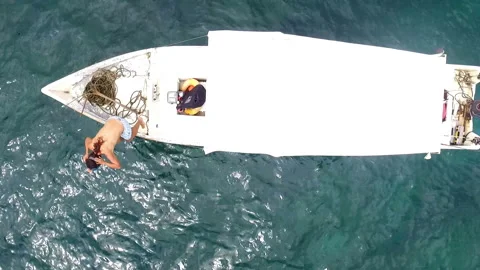 Young girl jumping into pristine waters aerial drone shot Stock Footage 100090707