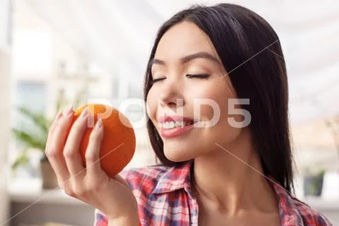 Young girl at kitchen healthy lifestyle standing breathing in smell of orange Stock Photos