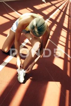 Young girl lacing up running boots at stadium Stock Photos