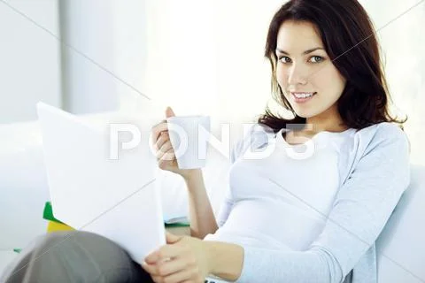 Young girl with laptop sitting at home, looking at camera and smiling Stock Photos