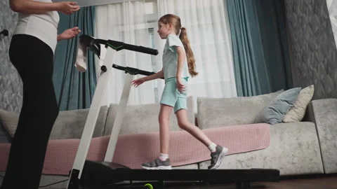 Young Girl Laughs While Balancing on Treadmill Under Coach Supervision Stock Footage 310208347