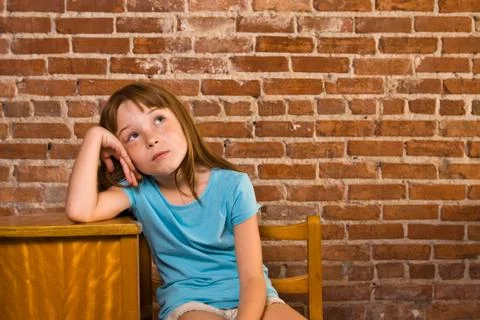 Young girl leaning on school desk thinking Stock Photos