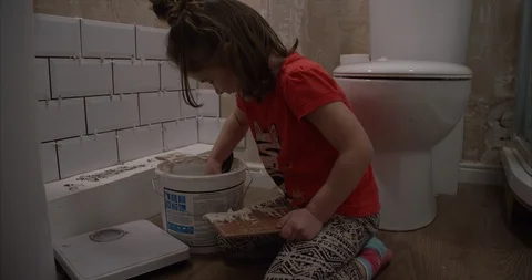 Young girl learning how to wall tile helping her dad to home renovate Stock Footage 101659826