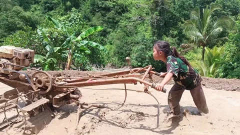 A young girl learning to operate a hand tractor in a muddy. Stock Footage 321930645