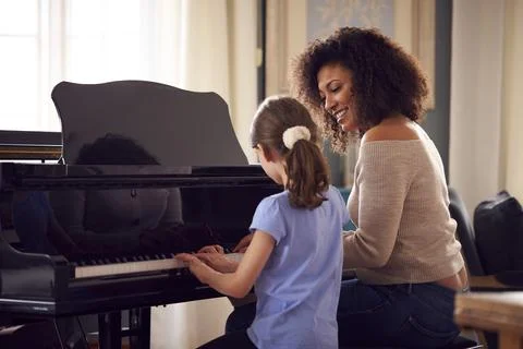 Young Girl Learning To Play Piano Having Lesson From Female Teacher Stock Photos