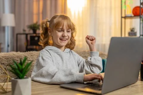 Young girl learning programming on laptop, celebrating in excitement after Stock Photos