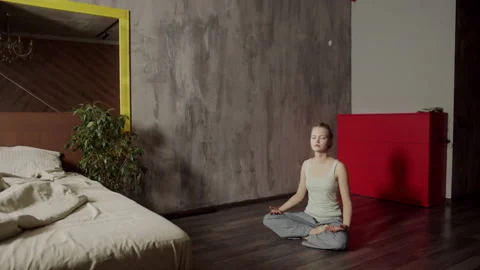 A young girl learns the basics of Buddhist yoga at home. Makes simple asanas to Stock Footage 145068725