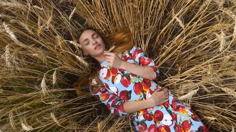Young girl lies in wheat and bites ear Stock Footage