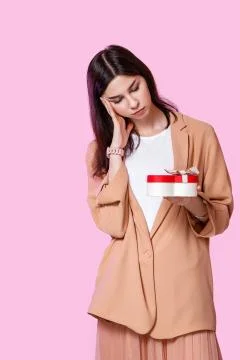 A young girl in a light jacket with a gift box in her hands. dissatisfied and Stock Photos