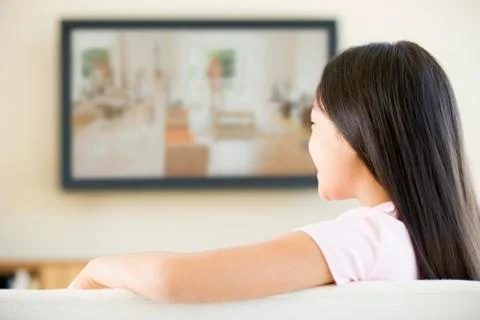Young girl in living room with flat screen television Stock Photos