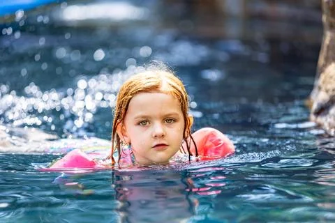 Young girl looking at camera while playing in the swimming pool. 스톡 사진