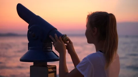 A Young Girl Looking At The Dramatic Sky With Her Telescope - Medium Shot Stockbeeldmateriaal 125780056