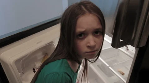 A young girl looks up from an empty fridge Stock Footage
