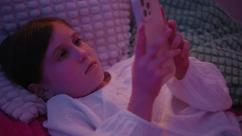 Young Girl Lying in Bed at Night Using Smartphone Stock Footage 345528400