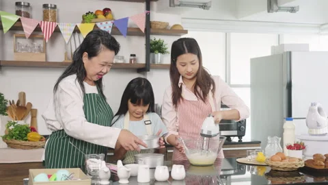 Young girl making a cake in the kitchen with her grandmother, mum Video stock 255478908