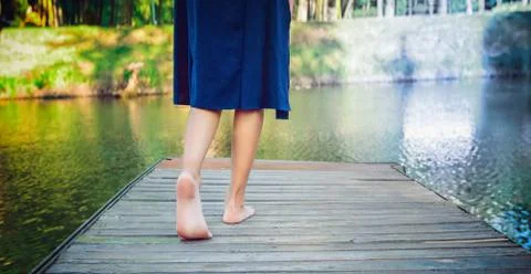 Young girl making a step bootlessly on the wooden pier and moving forward to  Stock Photos