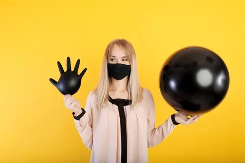 A young girl in a medical mask jerks a medical glove in her hands and a ballo Stock Photos