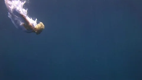 Young girl model free diver underwater white angel costume poses in Red Sea. Stock Footage