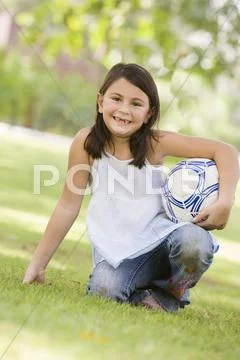 Young girl outdoors at park holding ball and smiling (selective focus) Stock Photos