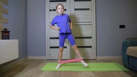Young girl performing side steps with resistance band during home fitness Stock Footage 344846702