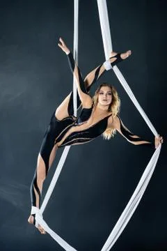 A young girl performs the acrobatic elements in the airrial silk. Studio Stock Photos