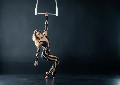 A young girl performs the acrobatic elements in the air trapeze. Studio shooting Stock Photos