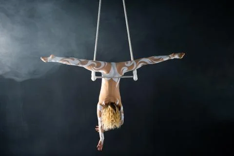 A young girl performs the acrobatic elements in the air trapeze. Studio shooting Stock Photos