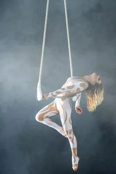 A young girl performs the acrobatic elements in the air trapeze. Studio shooting Stock Photos