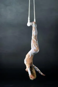 A young girl performs the acrobatic elements in the air trapeze. Studio shooting Stock Photos