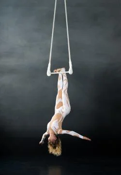 A young girl performs the acrobatic elements in the air trapeze. Studio shooting Stock Photos
