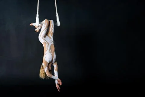 A young girl performs the acrobatic elements in the air trapeze. Studio shooting Stock Photos