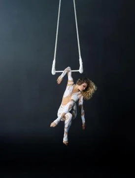 A young girl performs the acrobatic elements in the air trapeze. Studio shooting Stock Photos