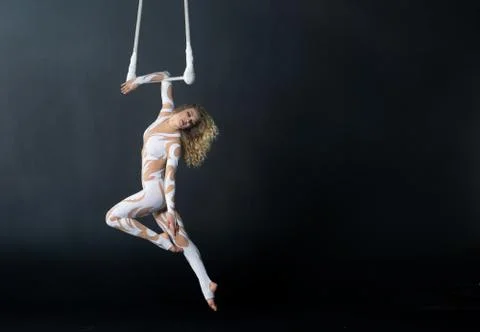 A young girl performs the acrobatic elements in the air trapeze. Studio shooting Stock Photos