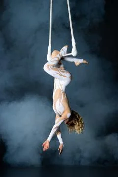 A young girl performs the acrobatic elements in the air trapeze. Studio shooting Stock Photos