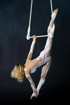 A young girl performs the acrobatic elements in the air trapeze. Studio shooting Stock Photos