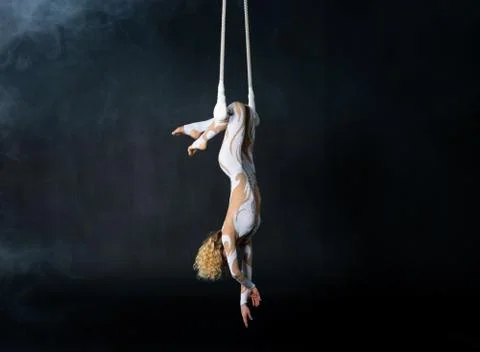 A young girl performs the acrobatic elements in the air trapeze. Studio shooting Stock Photos