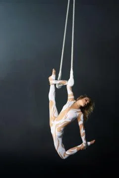 A young girl performs the acrobatic elements in the air trapeze. Studio shooting Stock Photos