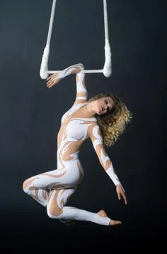 A young girl performs the acrobatic elements in the air trapeze. Studio shooting Stock Photos