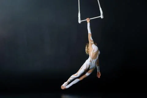 A young girl performs the acrobatic elements in the air trapeze. Studio shooting Stock Photos