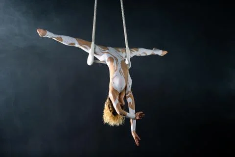 A young girl performs the acrobatic elements in the air trapeze. Studio shooting Stock Photos