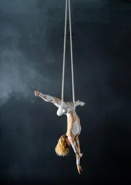A young girl performs the acrobatic elements in the air trapeze. Studio shooting Stock Photos