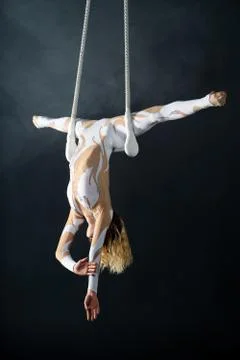 A young girl performs the acrobatic elements in the air trapeze. Studio shooting Stock Photos